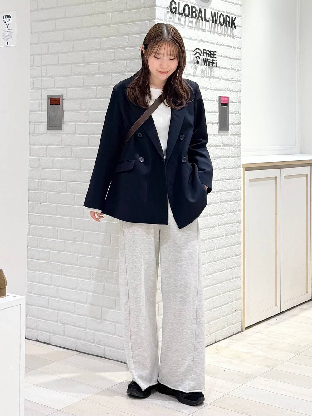 ブルー系のテーラードジャケット、ホワイト系のTシャツ/カットソー、ブラウン系のショルダーバッグを着用したレディースの冬コーディネートの2枚目の写真