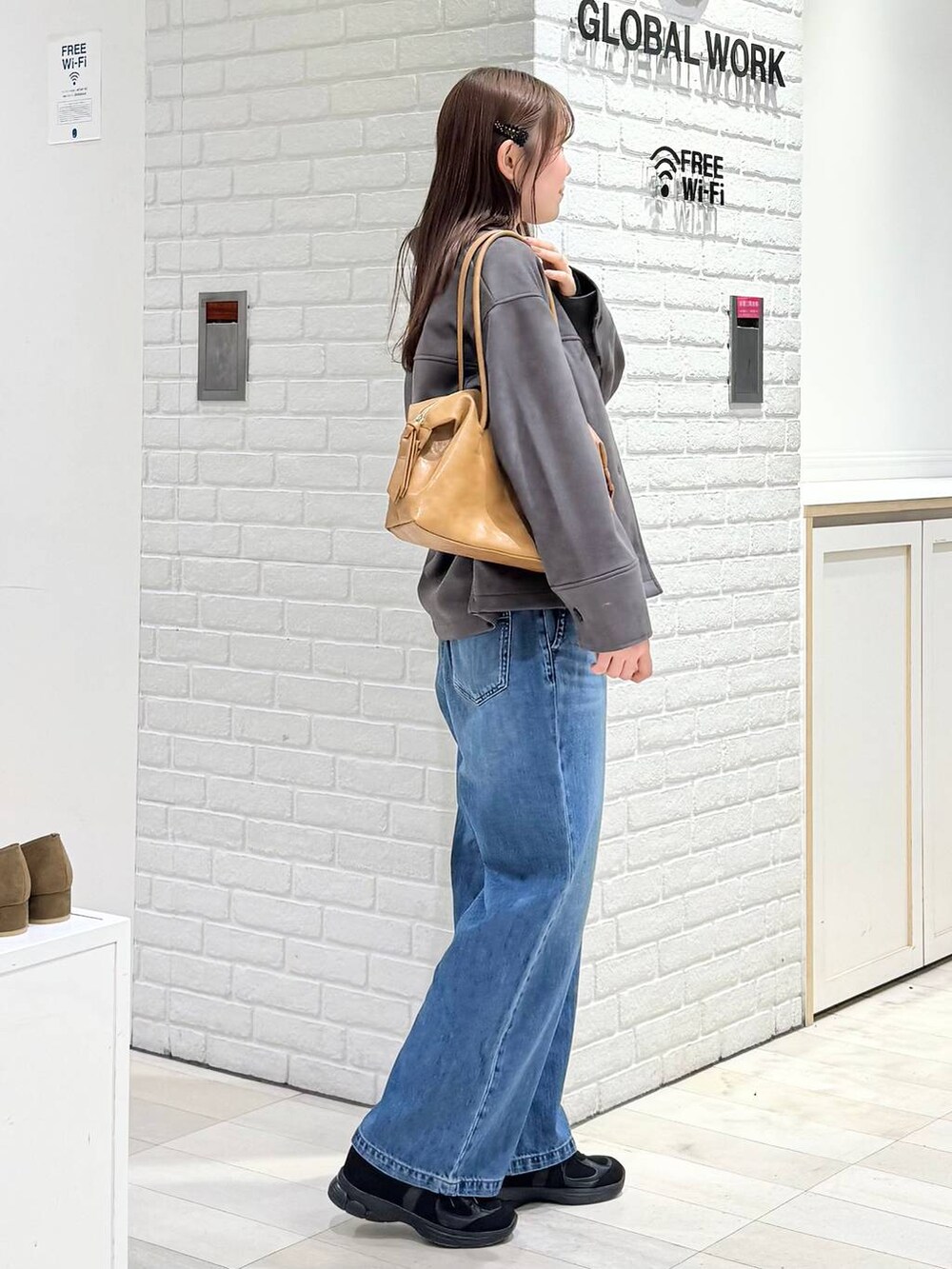 ブラウン系のボストンバッグ、ブルー系のデニムパンツ、グレー系のテーラードジャケットを着用したレディースの冬コーディネートの2枚目の写真