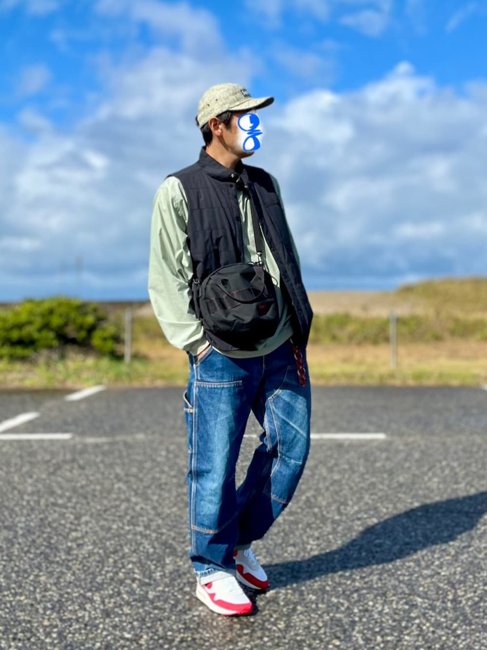 ブラック系のショルダーバッグ、ブルー系のナイロンジャケット、ブラック系のダウンベストを着用したメンズの秋コーディネートの2枚目の写真