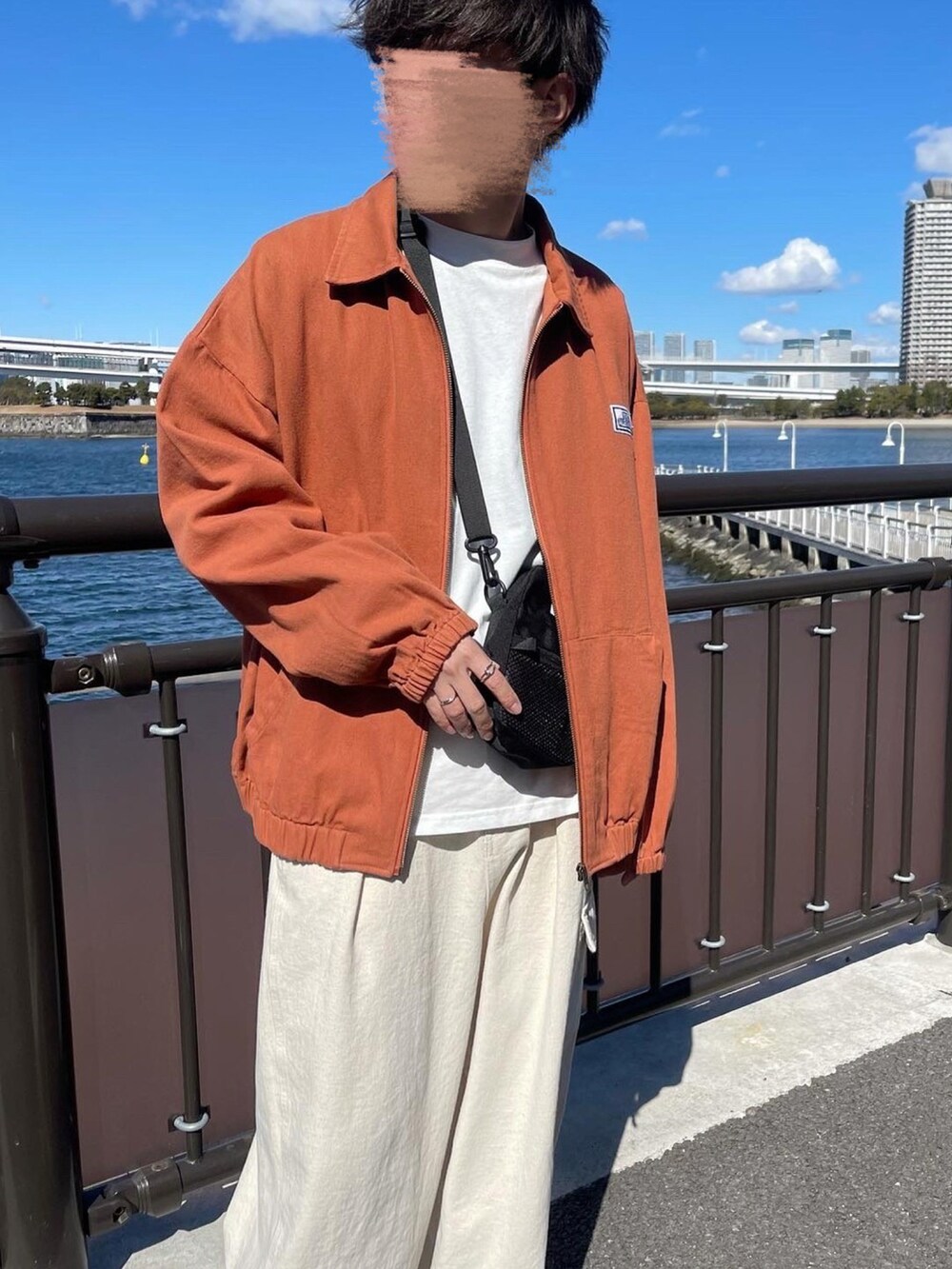 ホワイト系のその他パンツ、オレンジ系のブルゾン、ブラック系のショルダーバッグを着用したメンズの冬コーディネートの2枚目の写真