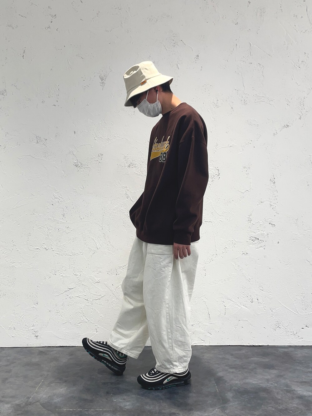 ブラウン系のスウェット、ホワイト系のハットを着用したメンズの冬コーディネートの2枚目の写真