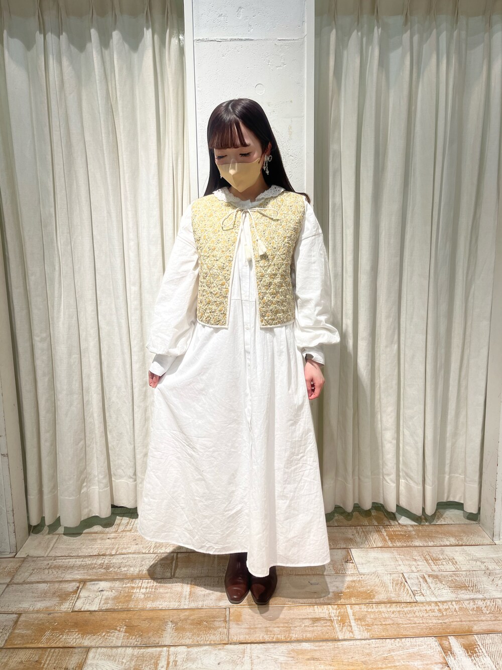 ホワイト系のシャツワンピース、ホワイト系のベスト、ホワイト系のバッグを着用したレディースの冬コーディネートの2枚目の写真