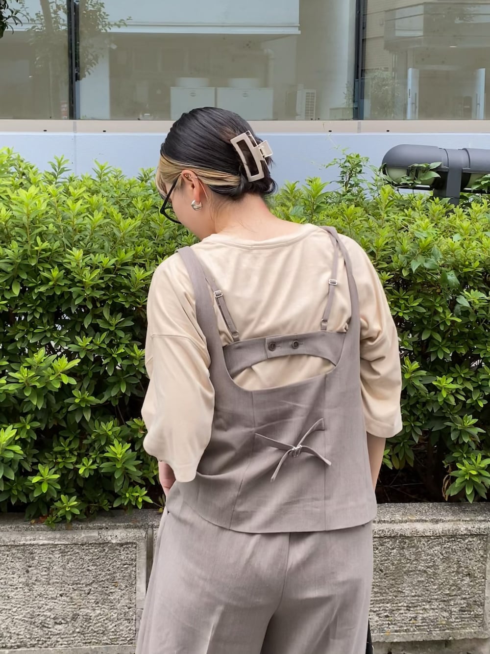 ブラウン系のベスト、ブラウン系のスラックス、ブラック系のトートバッグを着用したレディースの夏コーディネートの3枚目の写真