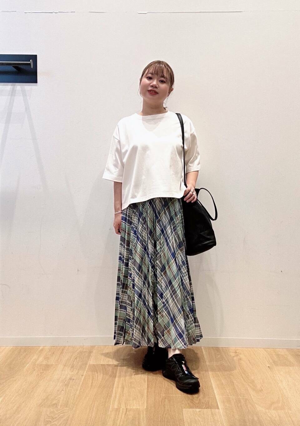 グリーン系のスカート、ホワイト系のTシャツ/カットソー、ブラック系のスニーカーを着用したレディースの夏コーディネートの2枚目の写真