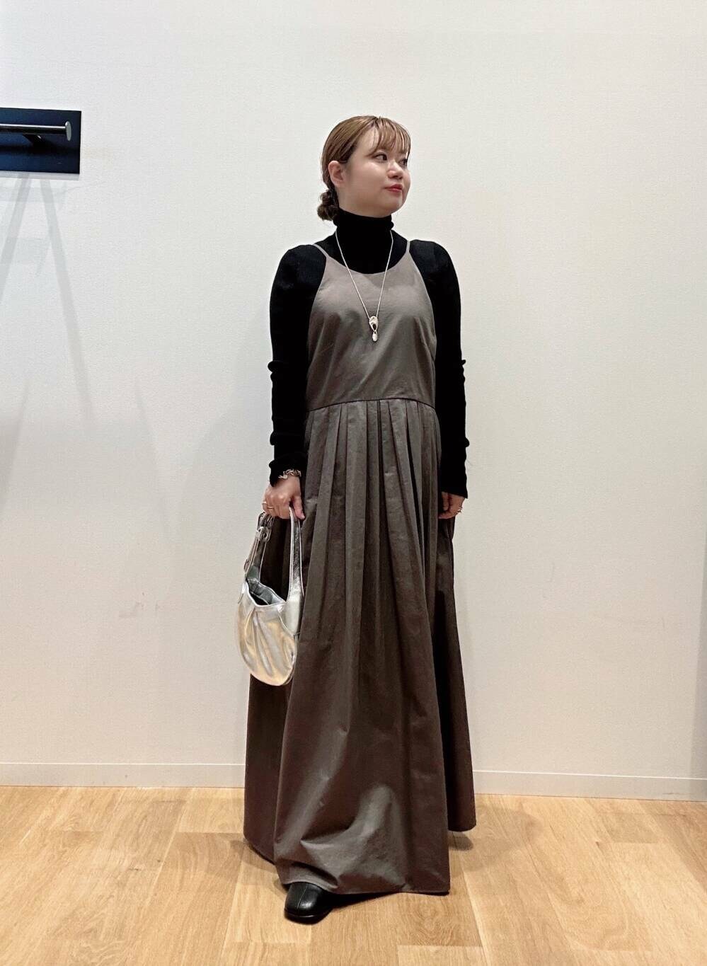 グリーン系のワンピース、ブラック系のニット/セーター、ブラック系のブーツを着用したレディースの秋コーディネートの4枚目の写真