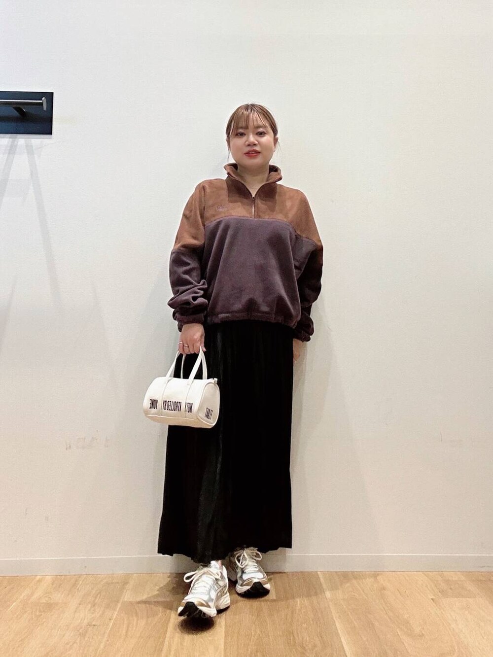 ブラウン系のTシャツ/カットソー、ホワイト系のスニーカー、ブラック系のスカートを着用したレディースの秋コーディネートの4枚目の写真