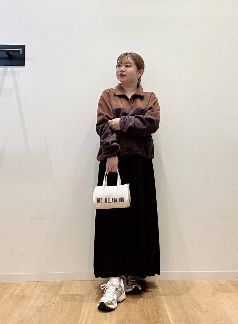 ブラウン系のTシャツ/カットソー、ホワイト系のスニーカー、ブラック系のスカートを着用したレディースの秋コーディネートの2枚目の写真