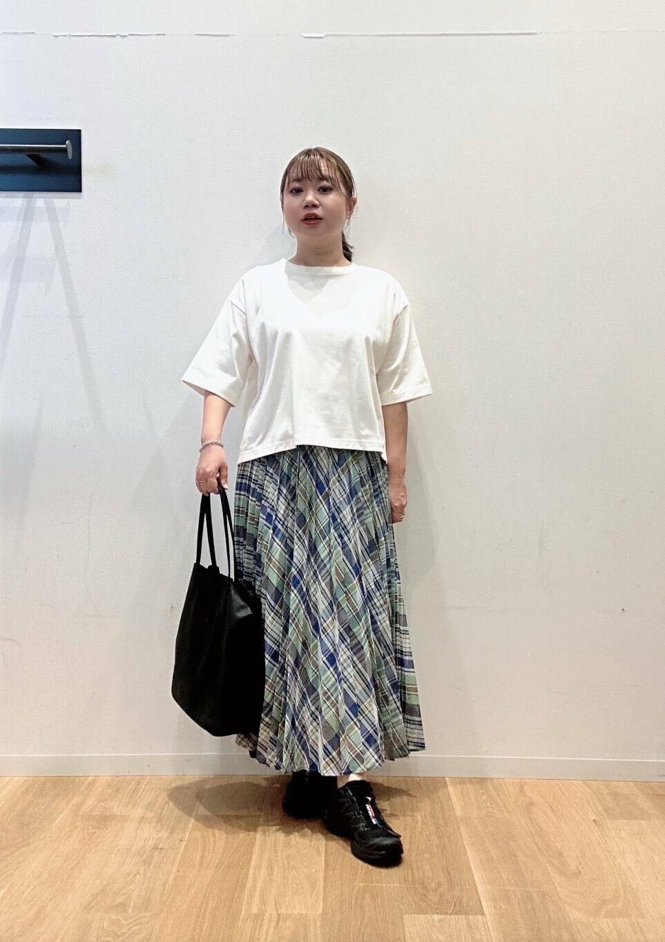 グリーン系のスカート、ホワイト系のTシャツ/カットソー、ブラック系のスニーカーを着用したレディースの夏コーディネートの3枚目の写真