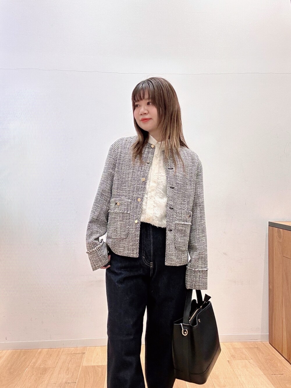 ブラック系のノーカラージャケット、ブルー系のデニムパンツ、ブラック系のハンドバッグを着用したレディースの冬コーディネートの5枚目の写真