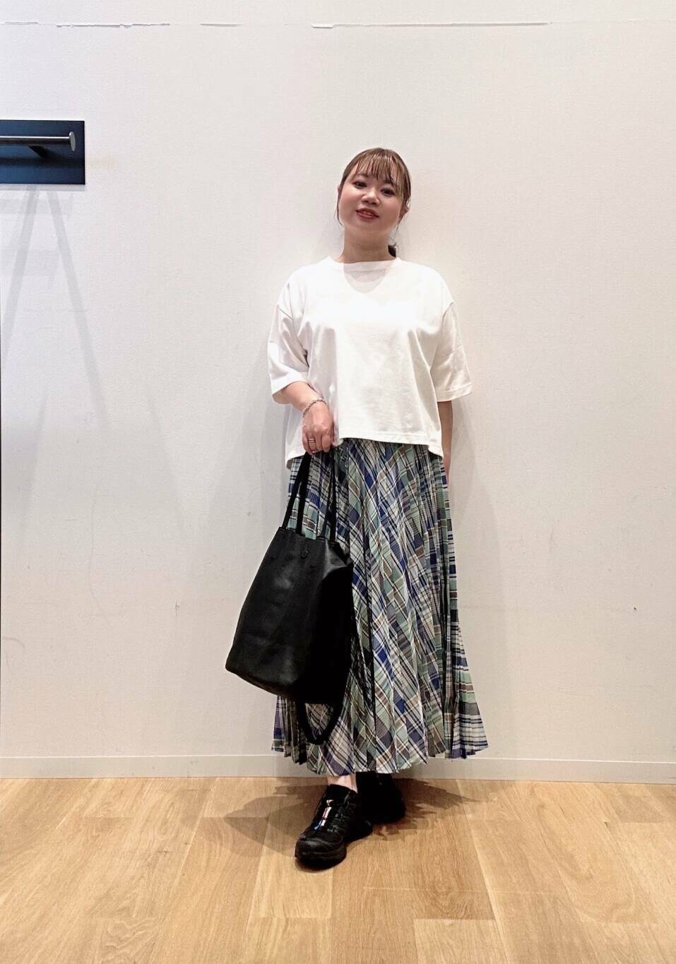 グリーン系のスカート、ホワイト系のTシャツ/カットソー、ブラック系のスニーカーを着用したレディースの夏コーディネートの4枚目の写真