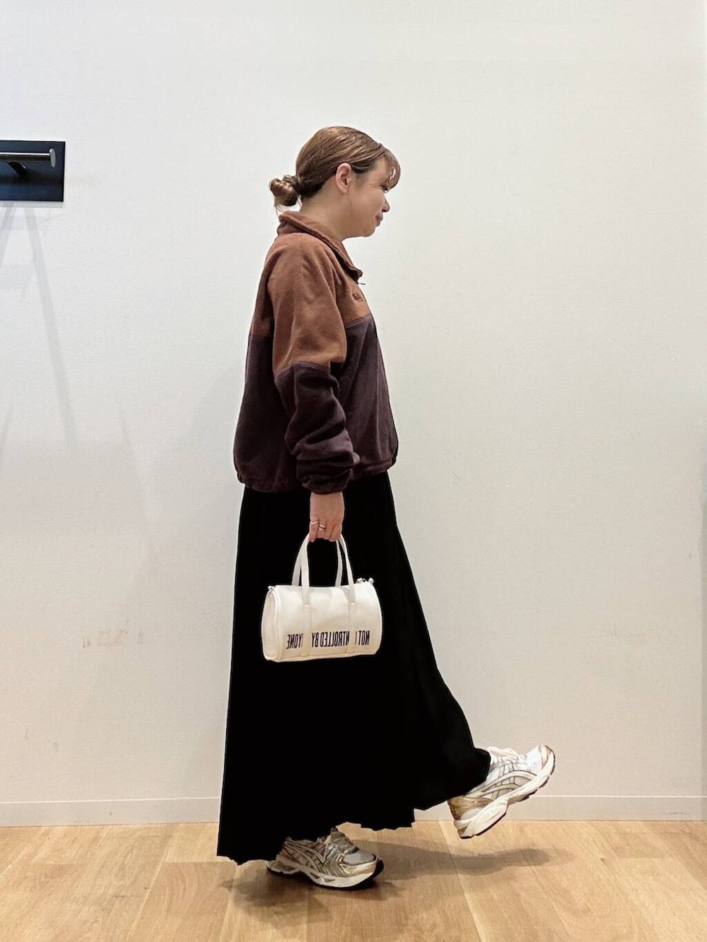 ブラウン系のTシャツ/カットソー、ホワイト系のスニーカー、ブラック系のスカートを着用したレディースの秋コーディネートの3枚目の写真