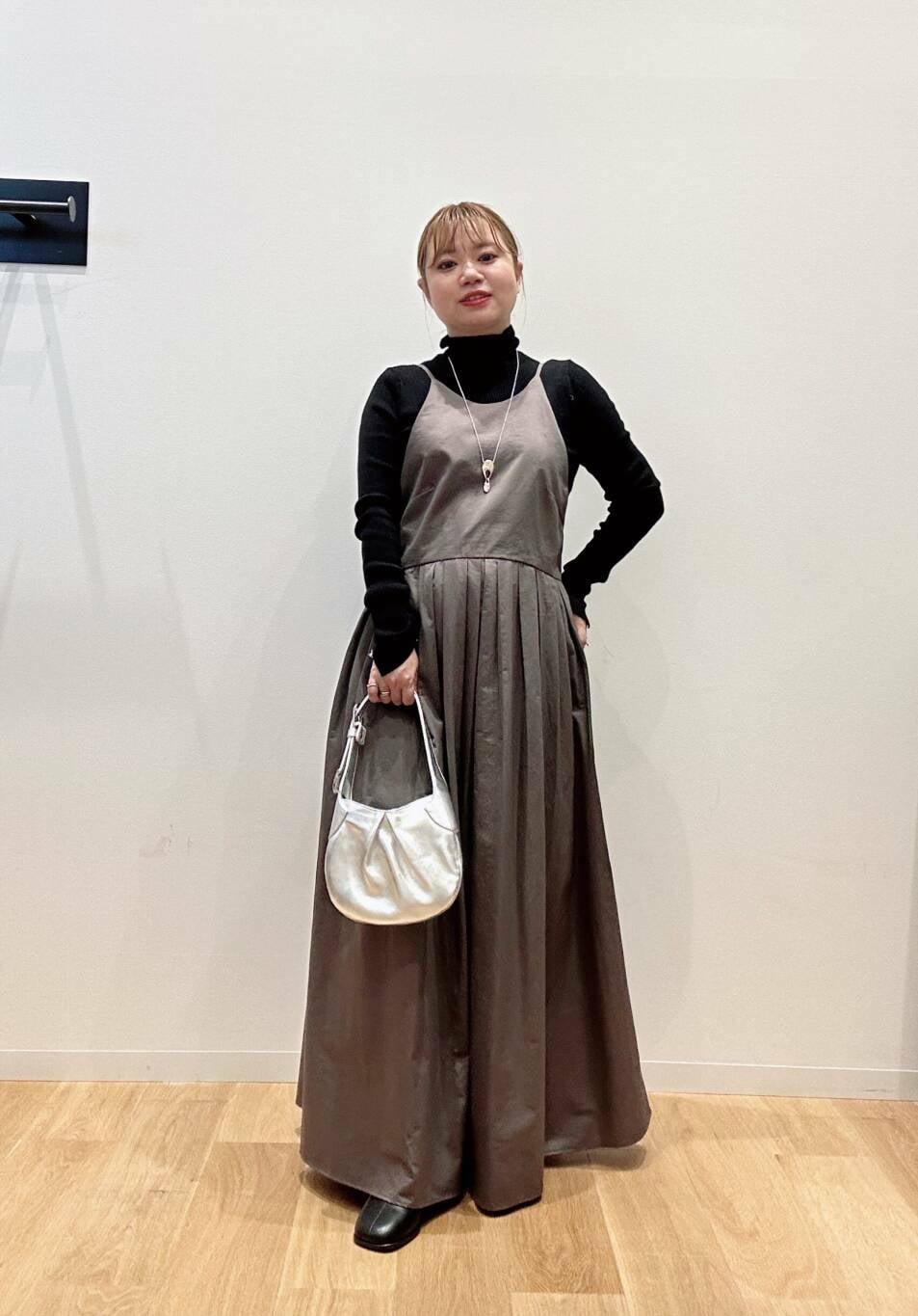 グリーン系のワンピース、ブラック系のニット/セーター、ブラック系のブーツを着用したレディースの秋コーディネートの3枚目の写真