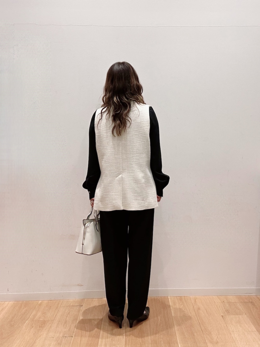 ホワイト系のハンドバッグ、ブラック系のその他パンツ、ブラック系のシャツ/ブラウスを着用したレディースの冬コーディネートの4枚目の写真