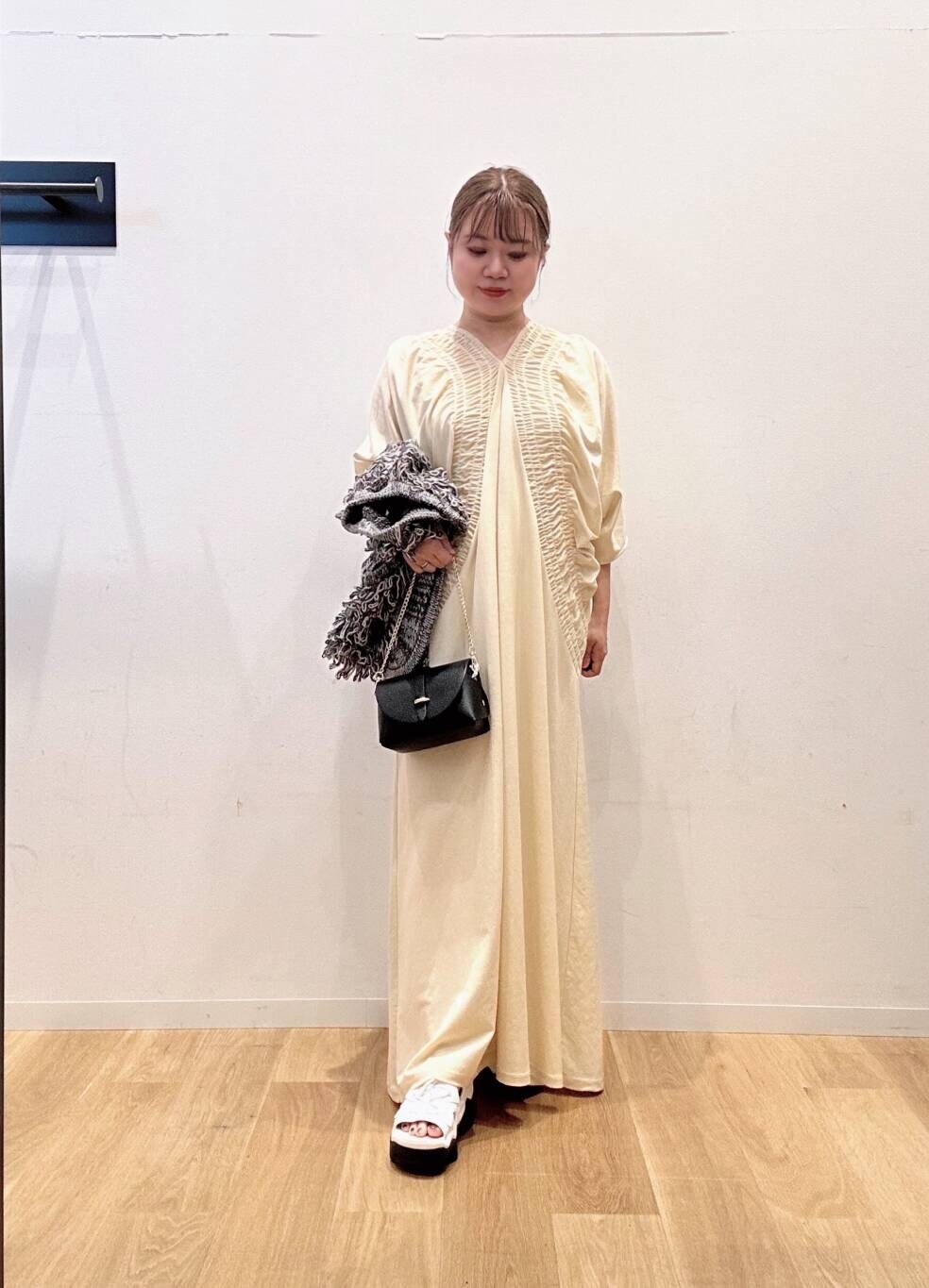 ブラック系のショルダーバッグ、ホワイト系のワンピース、グレー系のベストを着用したレディースの夏コーディネートの2枚目の写真