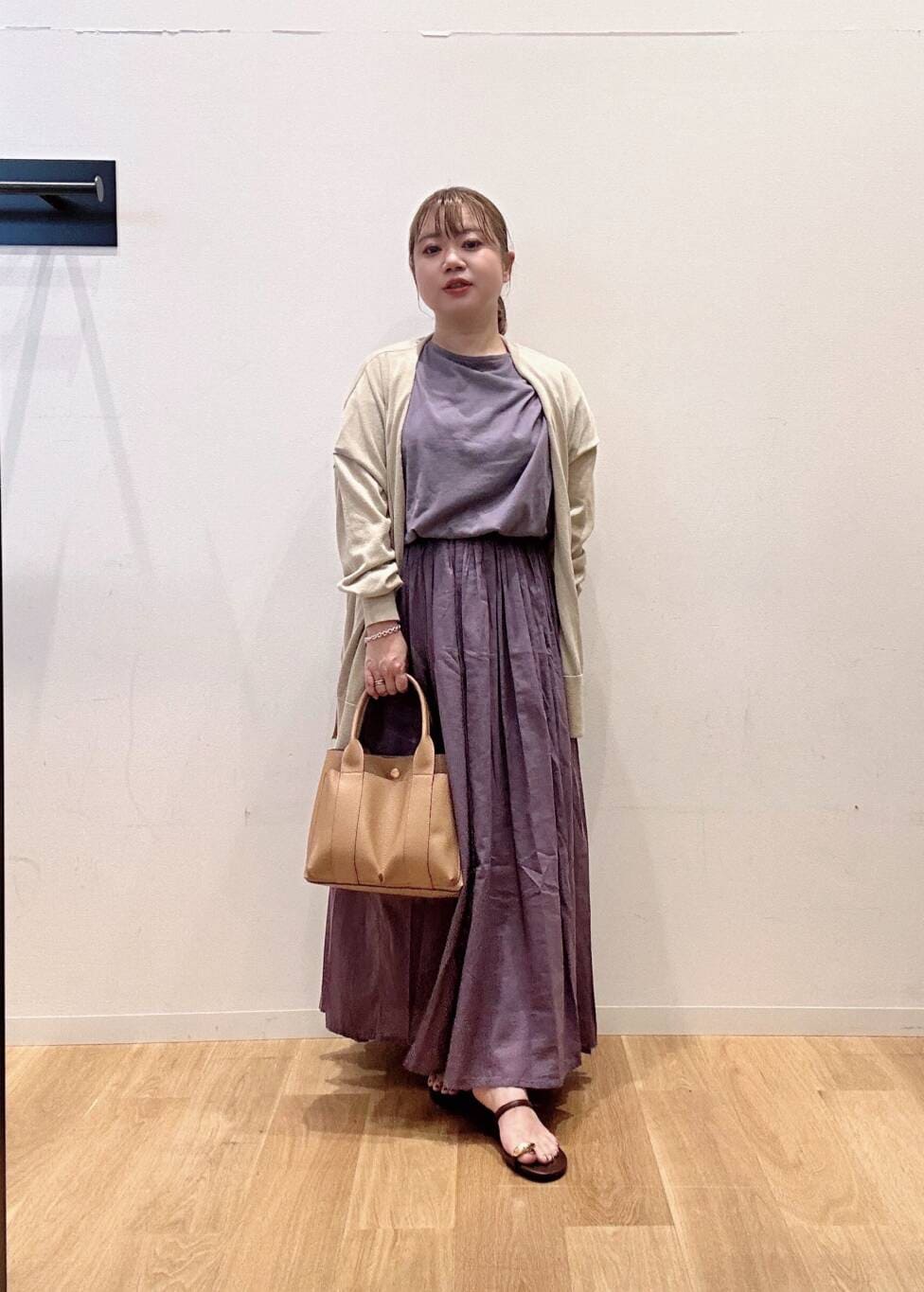 パープル系のワンピース、ベージュ系のトートバッグ、ベージュ系のカーディガン/ボレロを着用したレディースの夏コーディネートの2枚目の写真