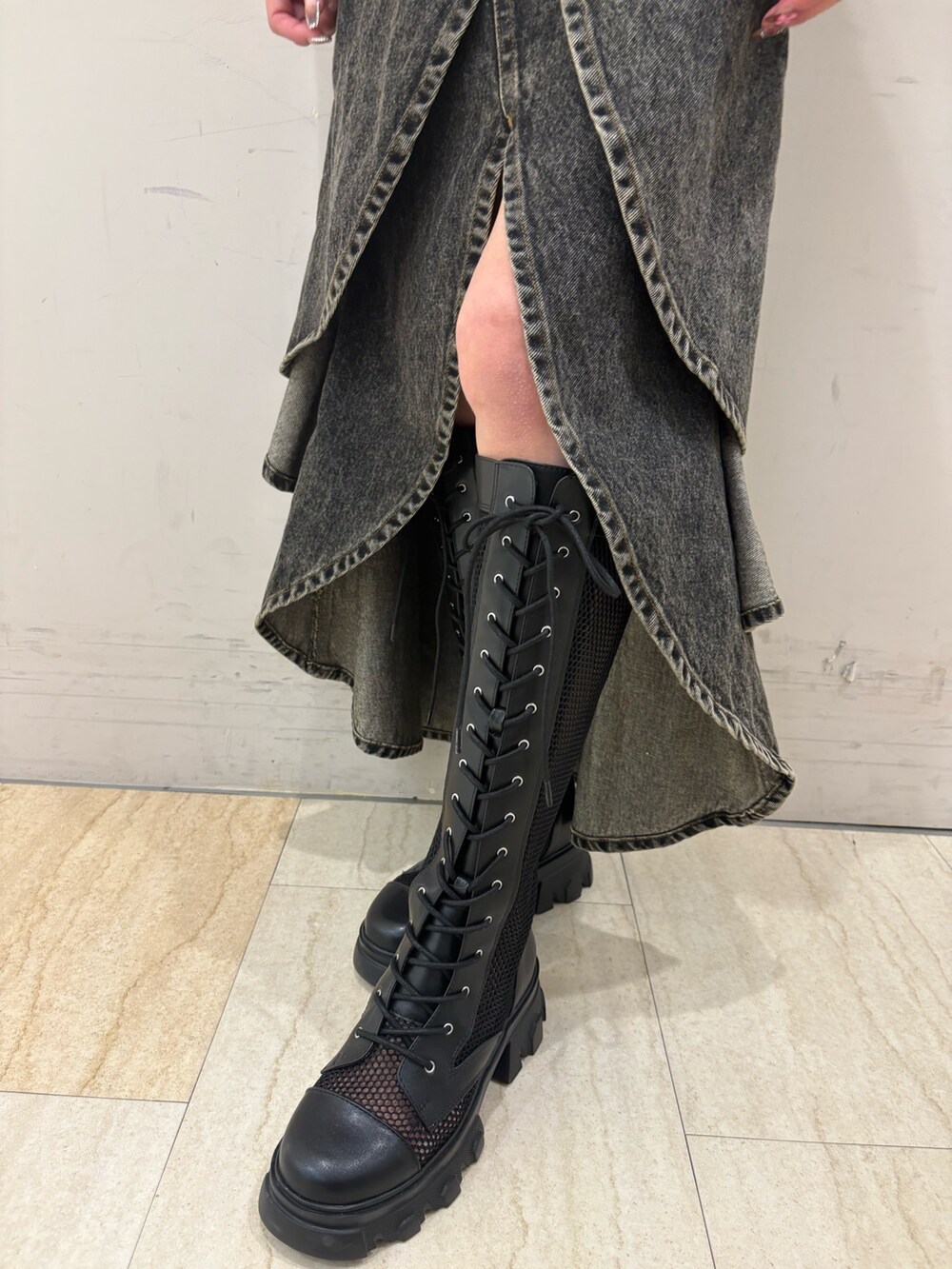 ブラック系のデニムスカート、ブラウン系のニット/セーター、ブラック系のブーツを着用したレディースの春コーディネートの4枚目の写真