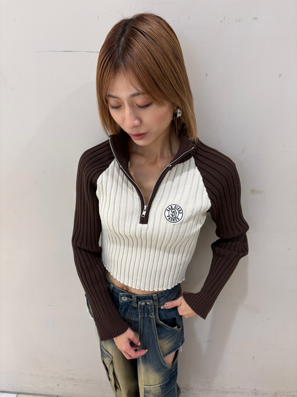 ブルー系のデニムパンツ、ベージュ系のニット/セーターを着用したレディースの冬コーディネートの2枚目の写真