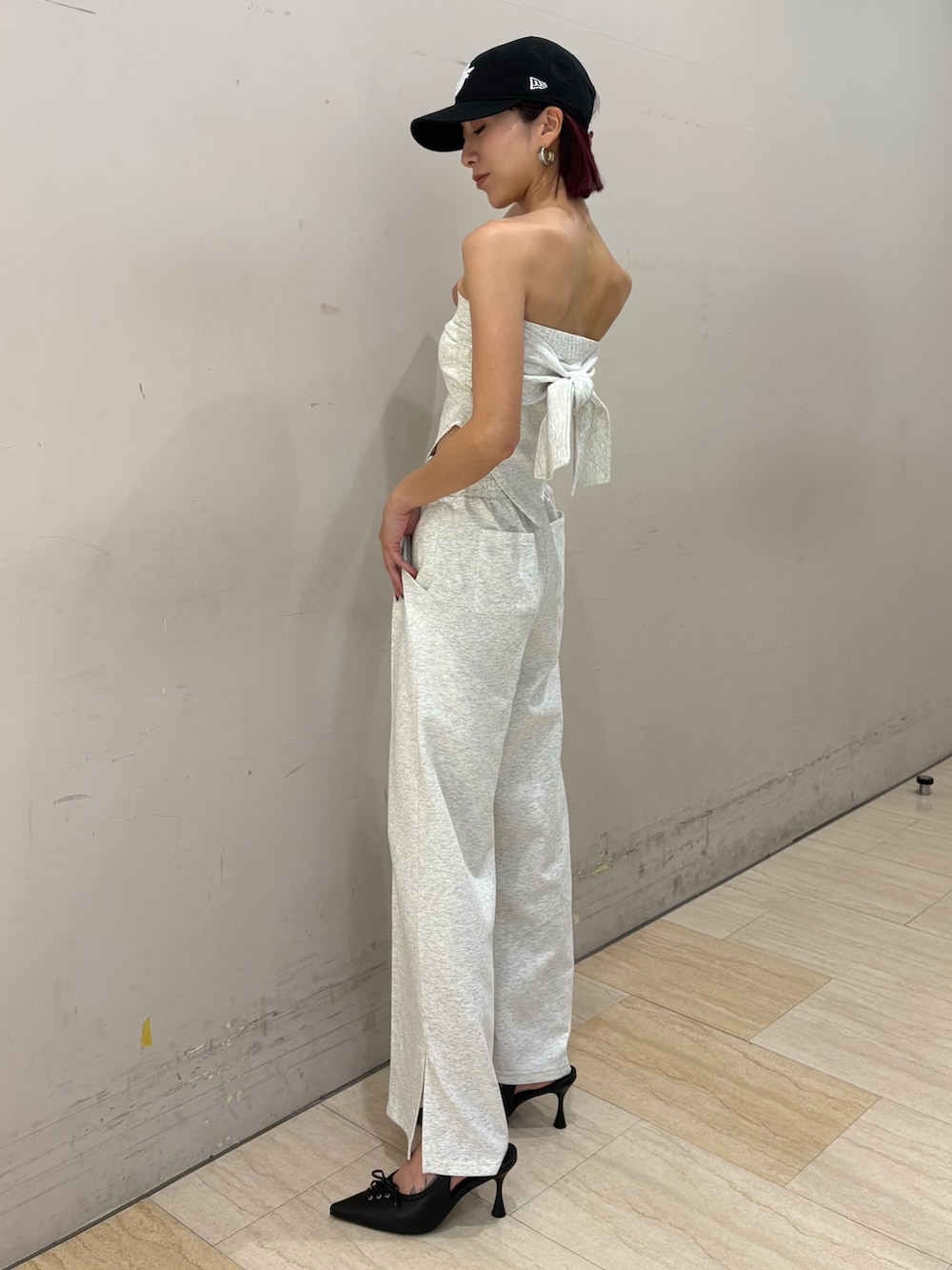 グレー系のワンピース、ブラック系のパンプス、ブラック系のキャップを着用したレディースの春コーディネートの2枚目の写真