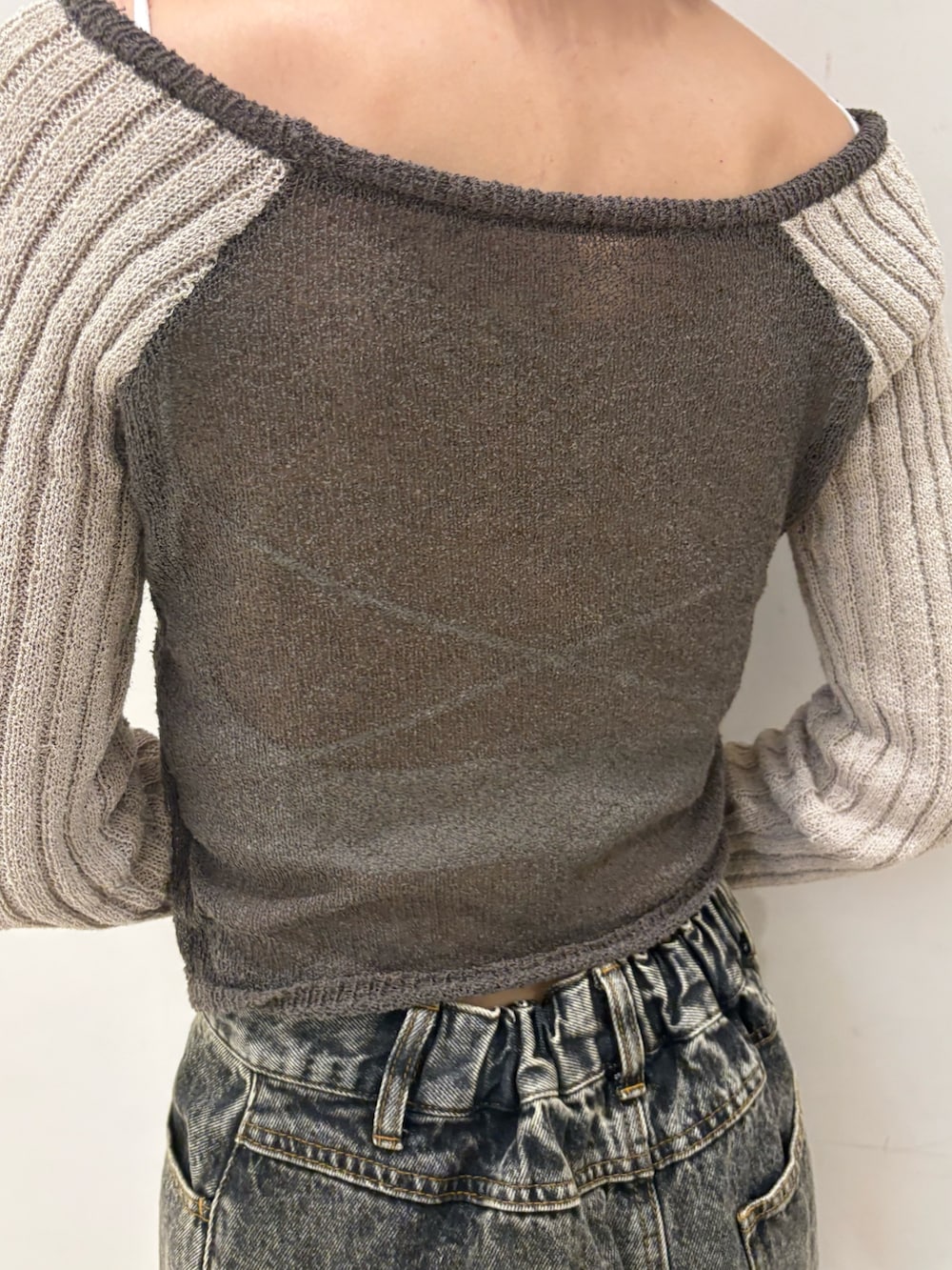 ブラック系のデニムスカート、ブラウン系のニット/セーター、ブラック系のブーツを着用したレディースの春コーディネートの3枚目の写真