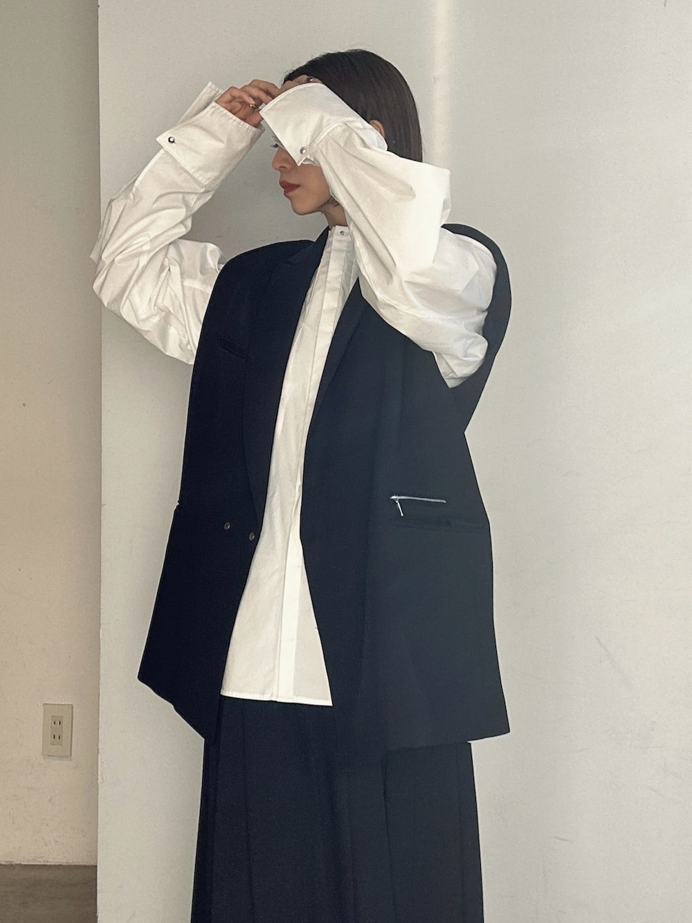 シルバー系のパンプス、ブラック系のテーラードジャケット、ブラック系のスカートを着用したレディースの冬コーディネートの6枚目の写真