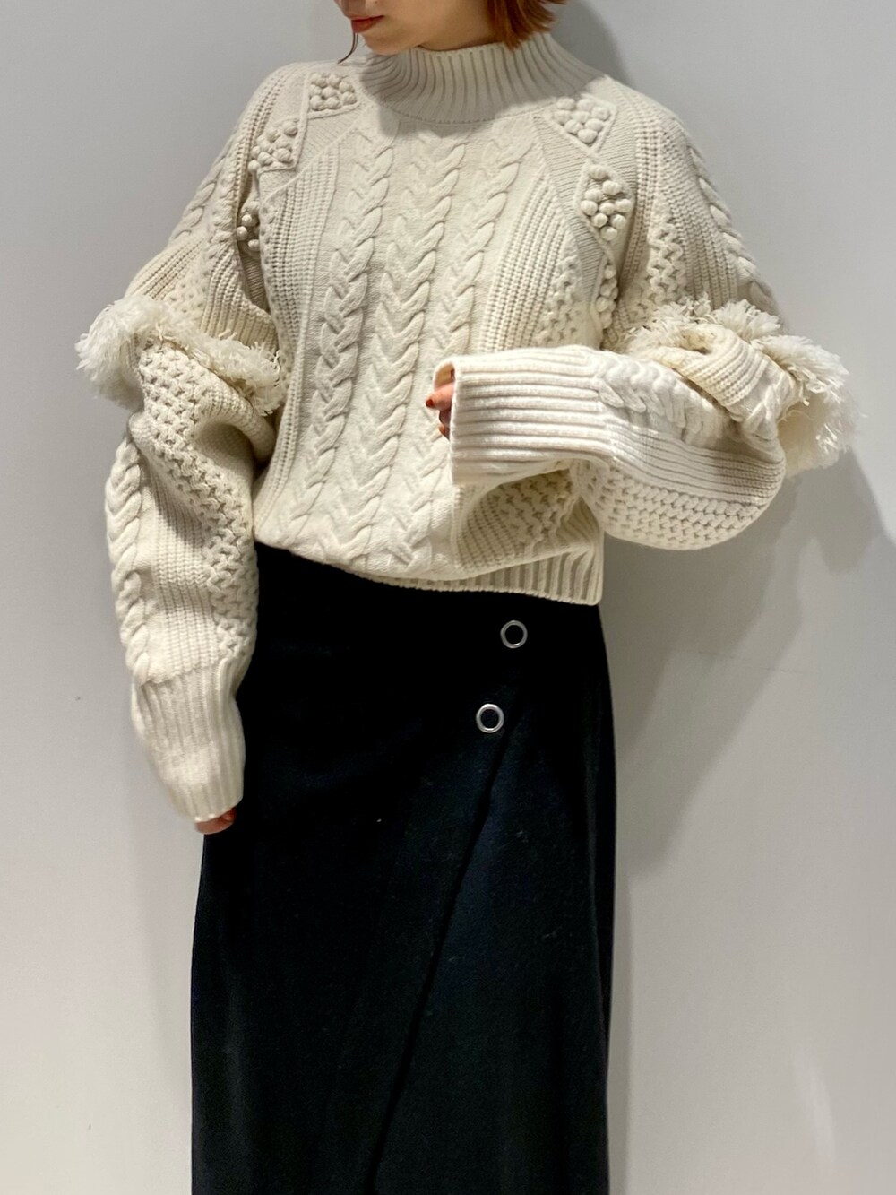 ブラック系のスカート、ブラック系のブーツ、ホワイト系のニット/セーターを着用したレディースの春コーディネートの7枚目の写真