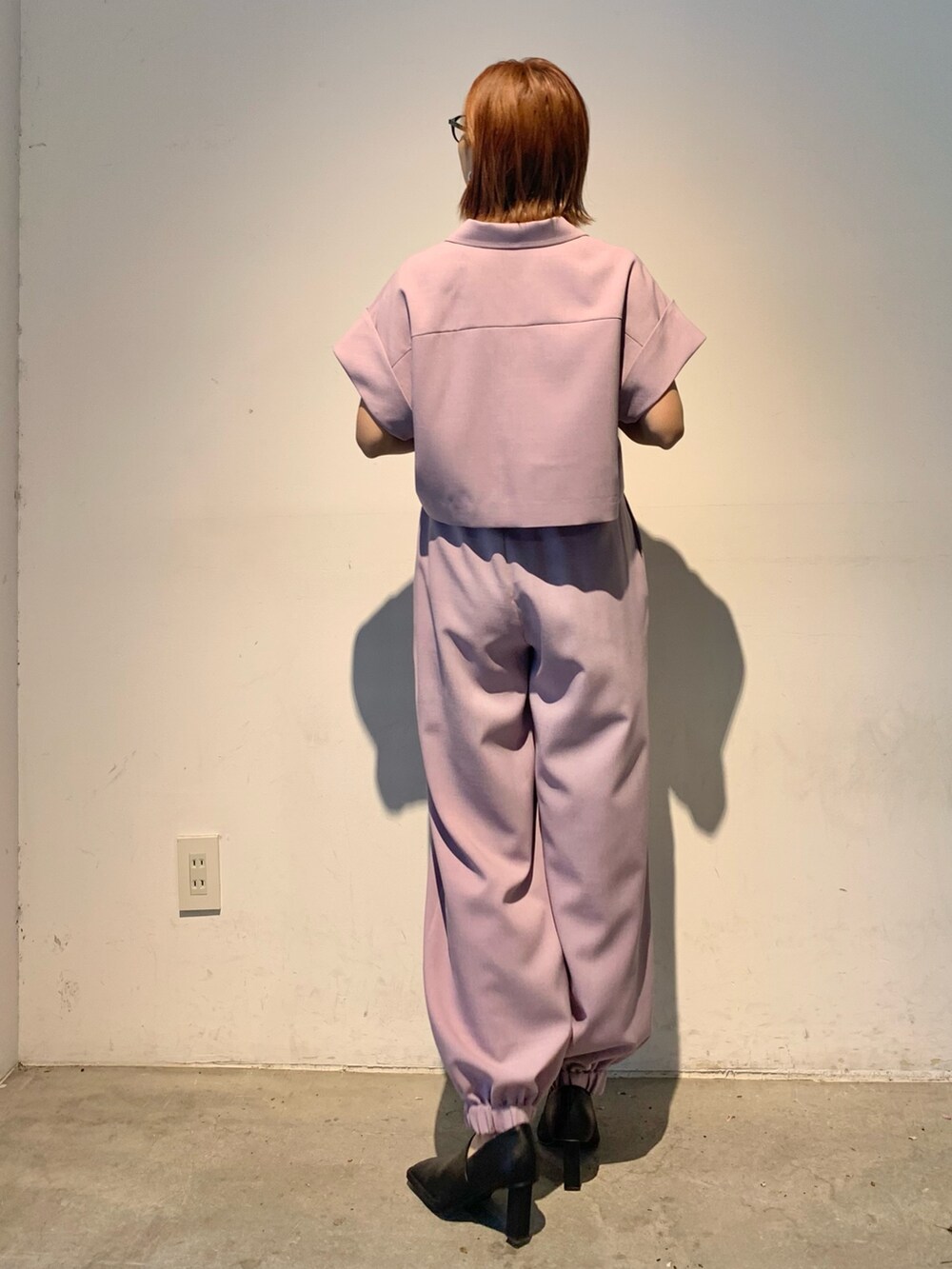 パープル系のテーラードジャケット、パープル系のスラックス、ブラック系のパンプスを着用したレディースの春コーディネートの4枚目の写真