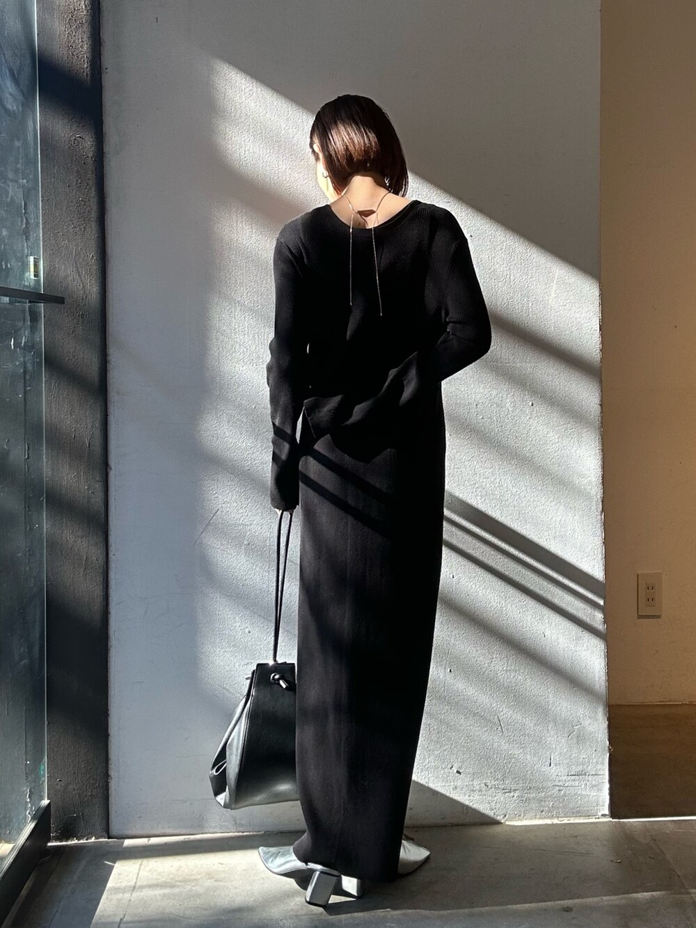 ブラック系のワンピース、シルバー系のパンプス、ブラック系のハンドバッグを着用したレディースの冬コーディネートの4枚目の写真