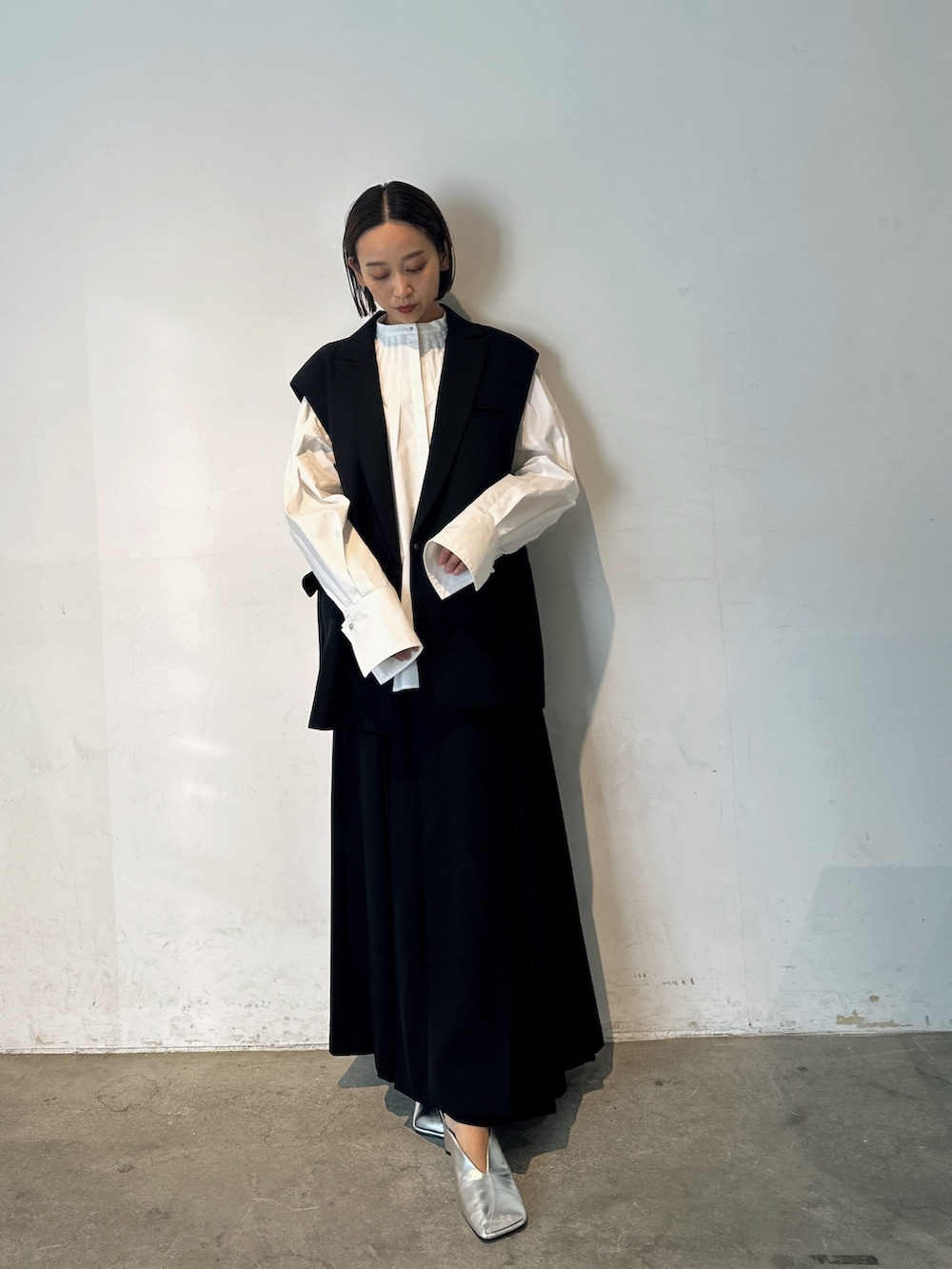 シルバー系のパンプス、ブラック系のテーラードジャケット、ブラック系のスカートを着用したレディースの冬コーディネートの2枚目の写真