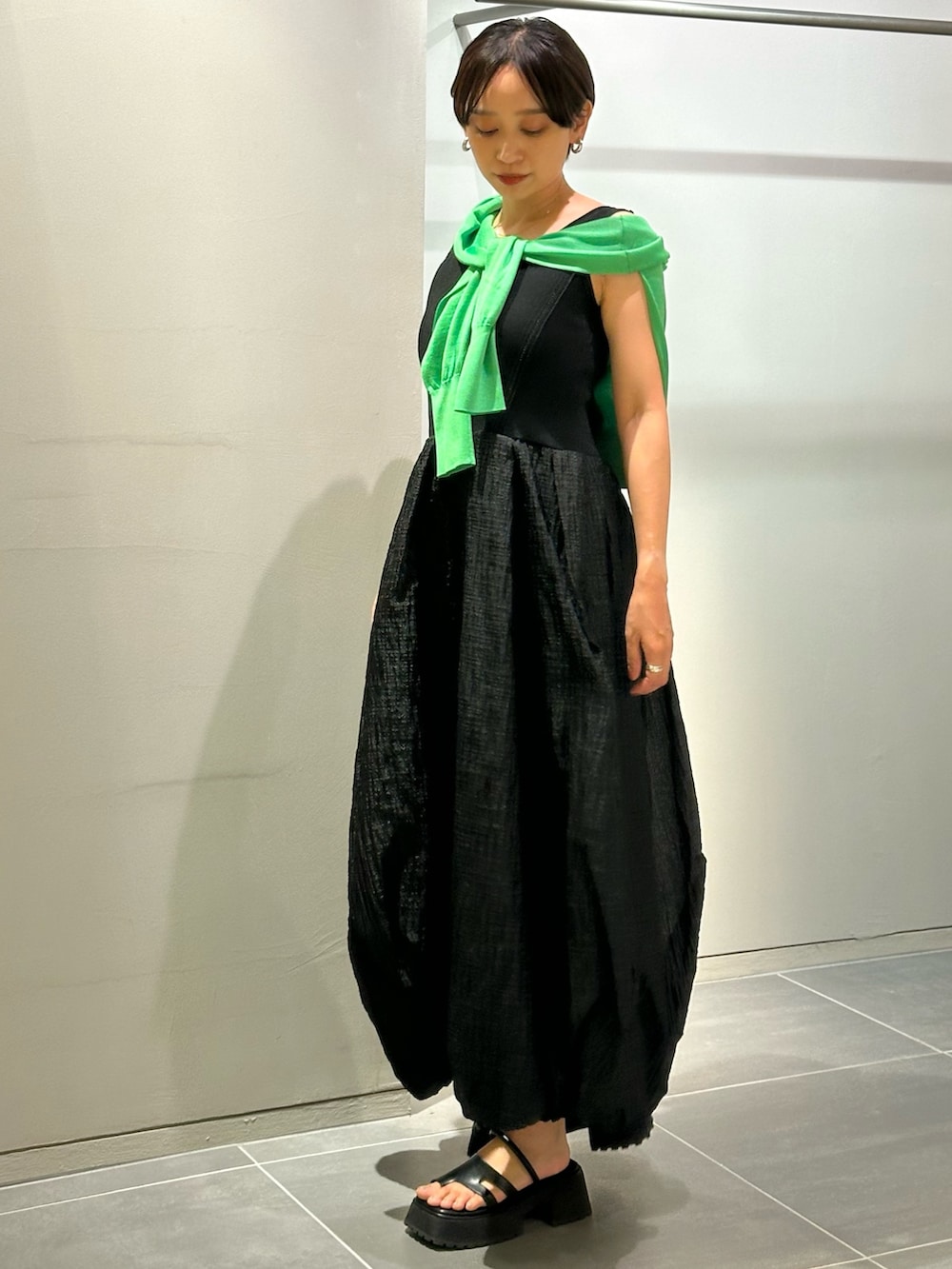 ブラック系のワンピース、ブラック系のサンダル、グリーン系のカーディガン/ボレロを着用したレディースの夏コーディネートの3枚目の写真