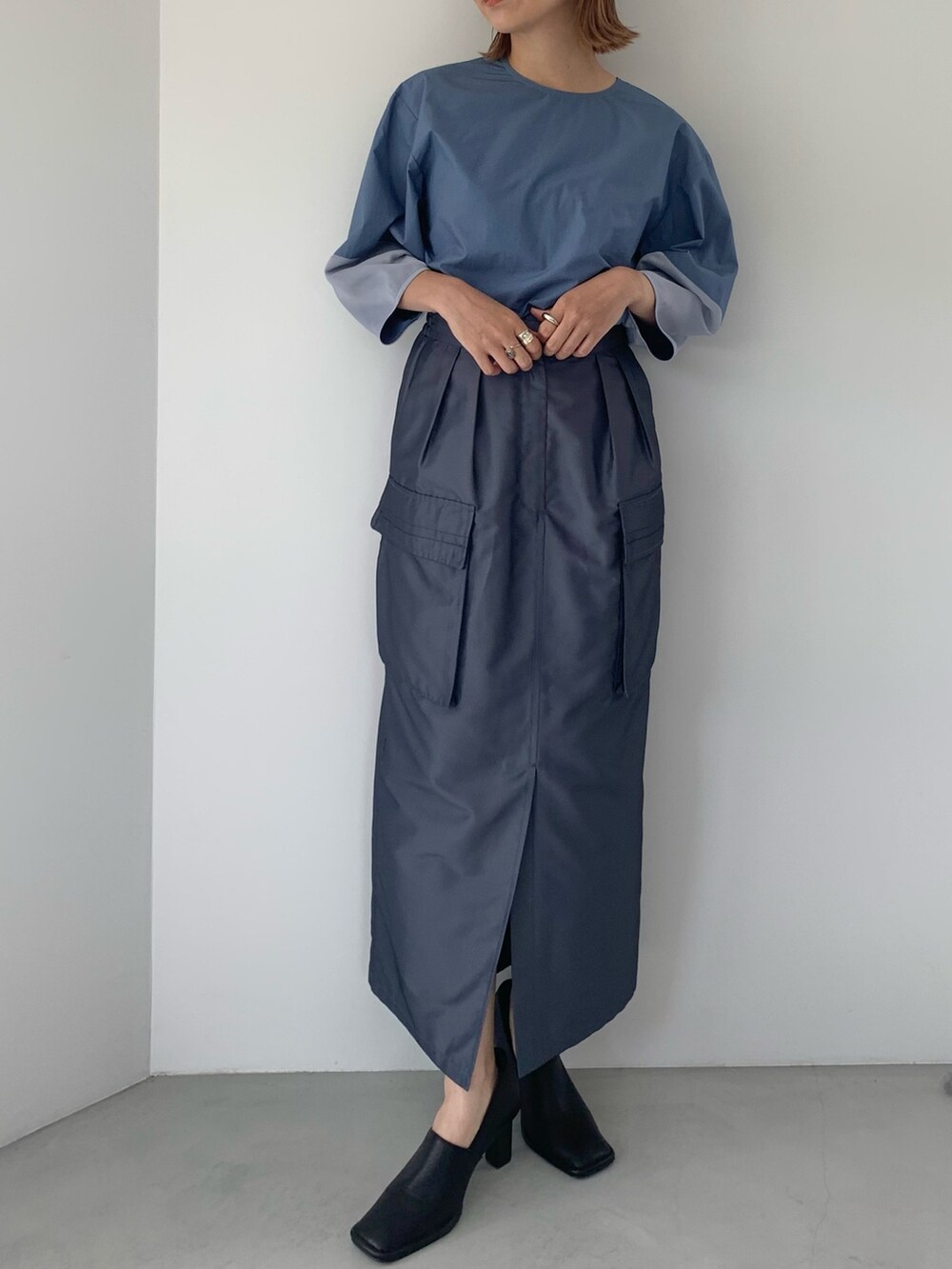ブラック系のパンプス、ブルー系のスカート、ブルー系のシャツ/ブラウスを着用したレディースの春コーディネートの2枚目の写真