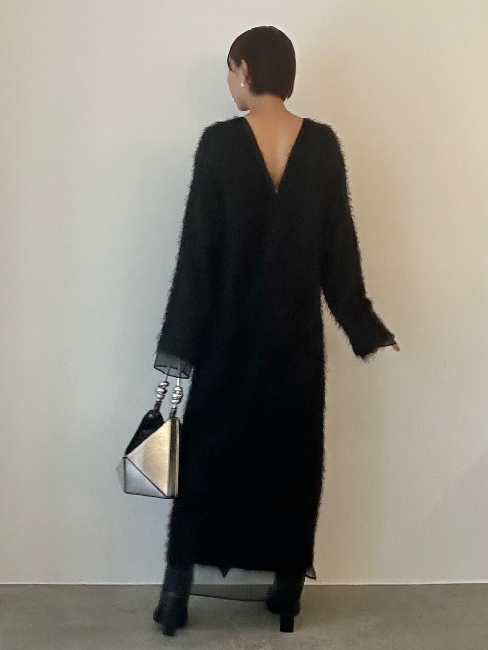 ブラック系のワンピース、シルバー系のハンドバッグ、ブラック系のブーツを着用したレディースの秋コーディネートの3枚目の写真