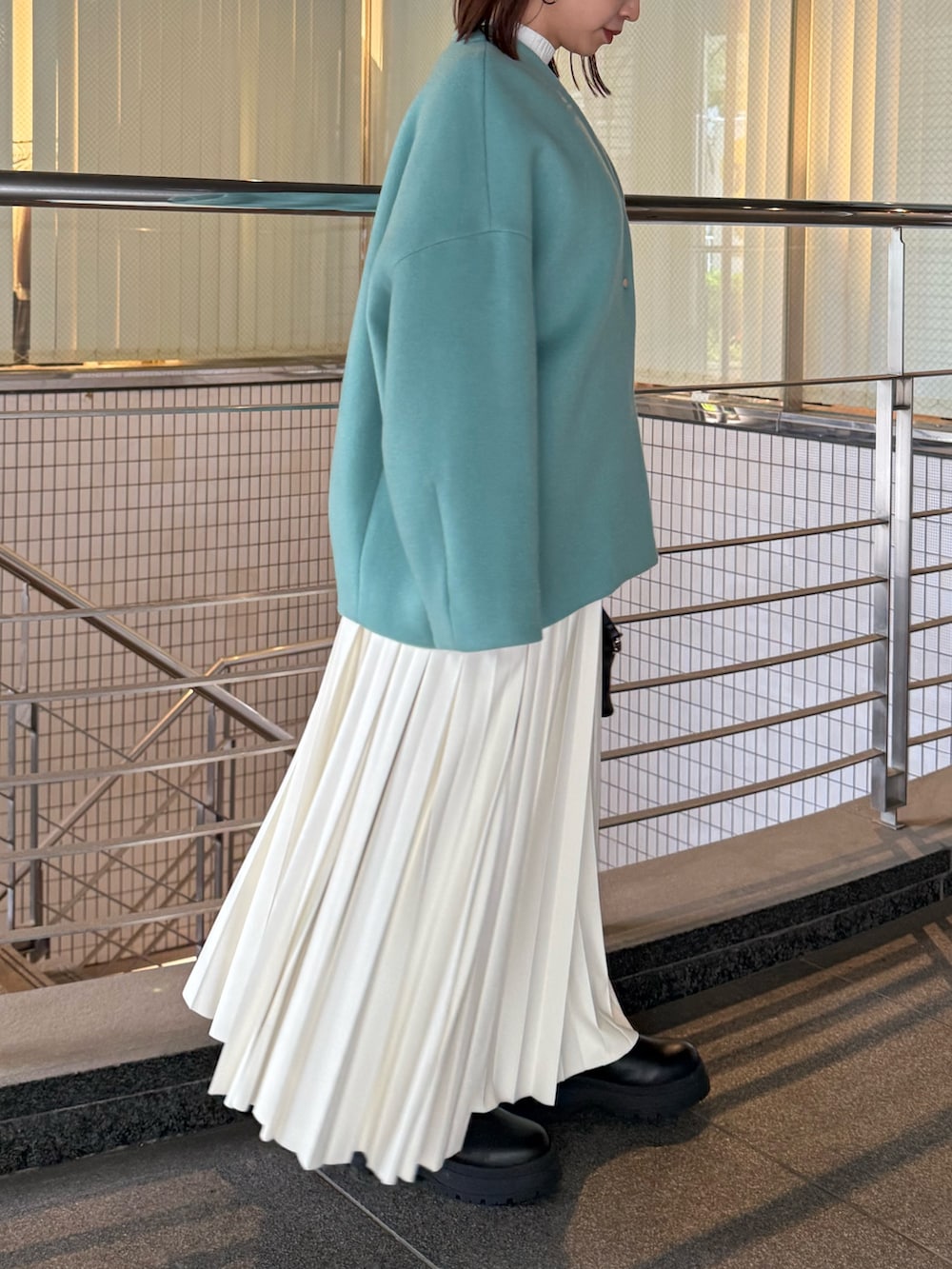 ホワイト系のニット/セーター、ホワイト系のスカート、グリーン系のノーカラージャケットを着用したレディースの秋コーディネートの3枚目の写真