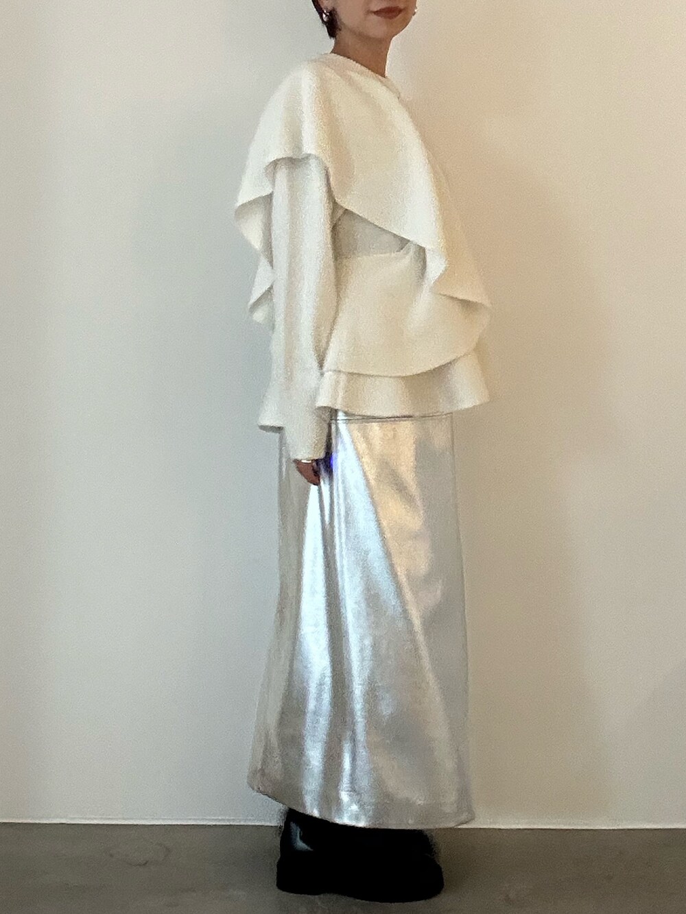 ホワイト系のニット/セーター、ブラック系のブーツ、シルバー系のスカートを着用したレディースの秋コーディネートの5枚目の写真