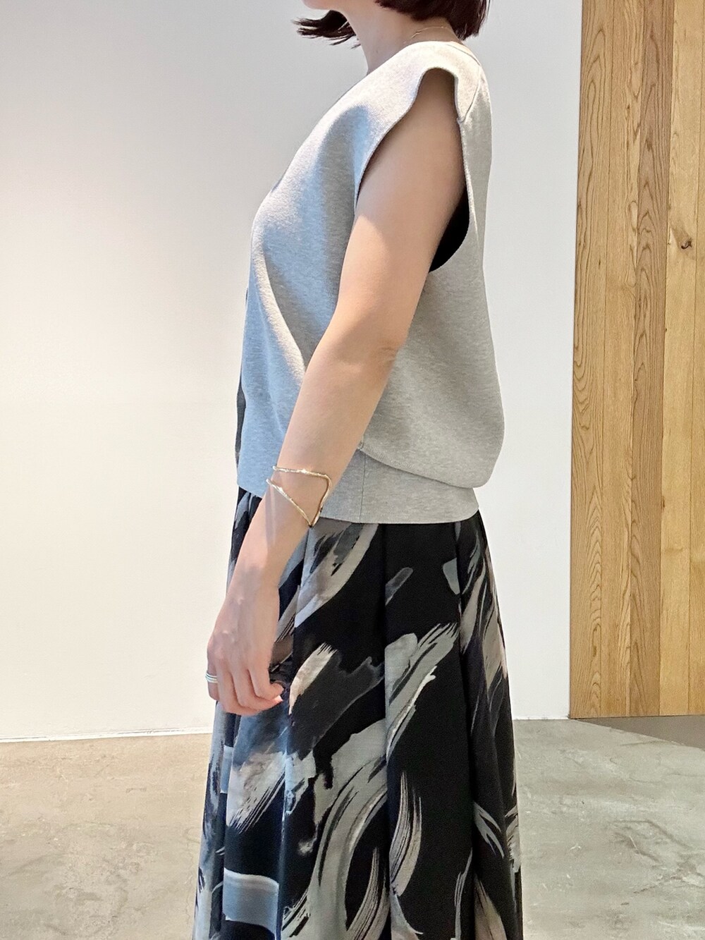 ブラック系のスカート、ホワイト系のサンダル、グレー系のニット/セーターを着用したレディースの春コーディネートの6枚目の写真