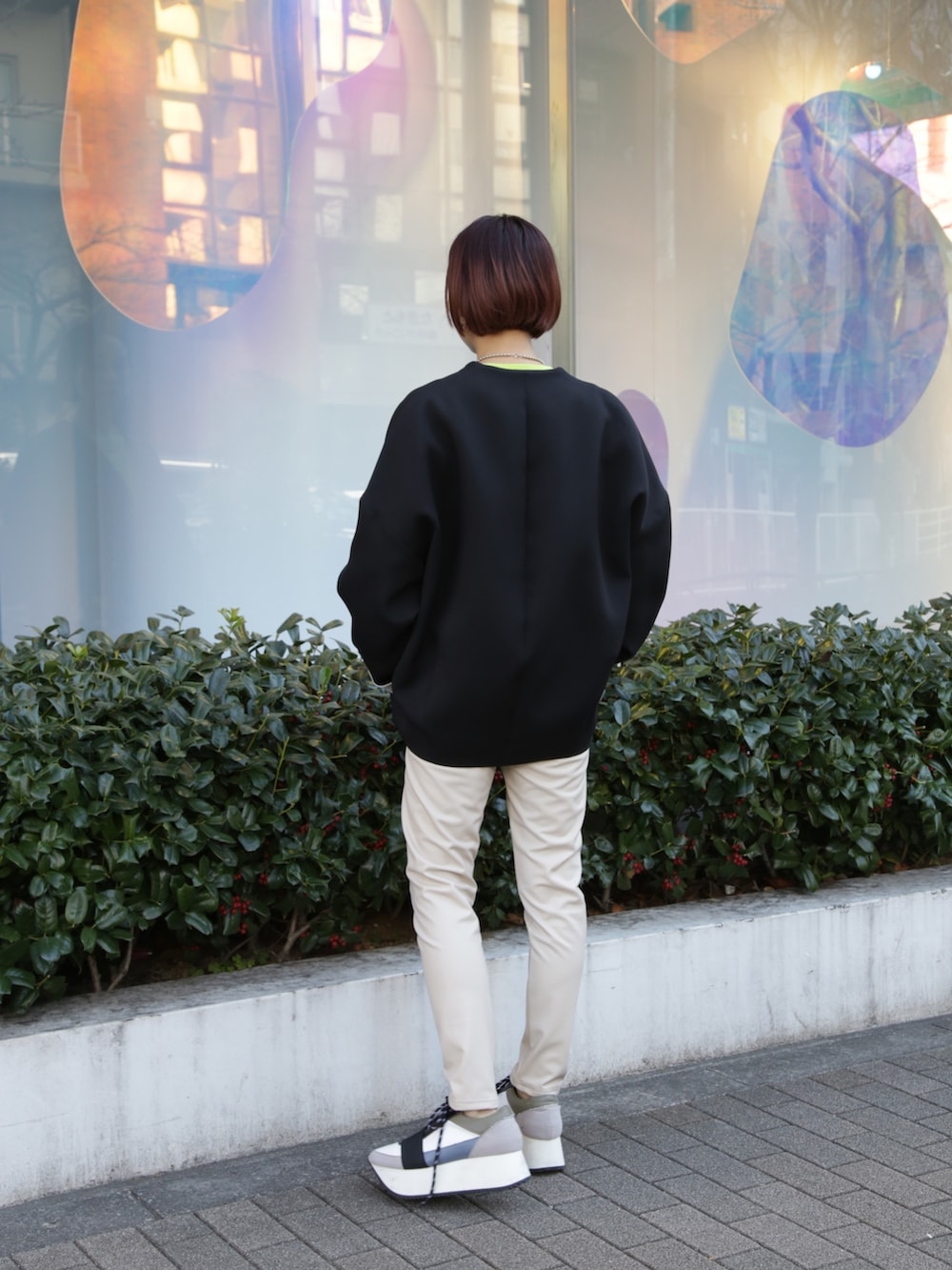 ブラック系のノーカラーコート、ベージュ系のその他パンツ、ブルー系のスニーカーを着用したレディースの冬コーディネートの4枚目の写真