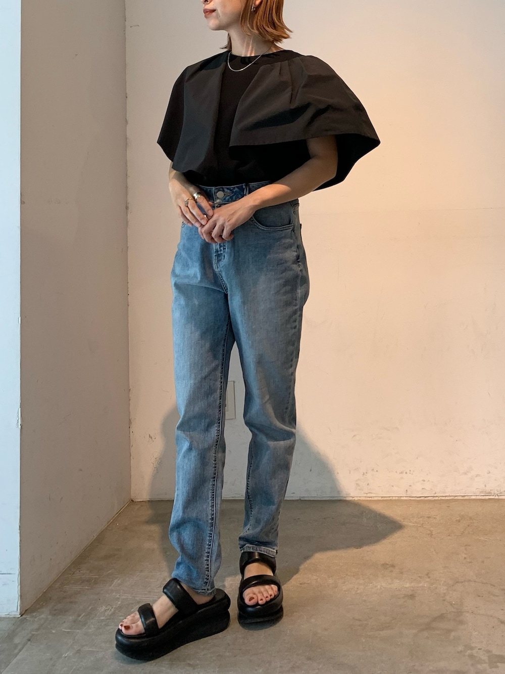 ブラック系のTシャツ/カットソー、ブルー系のデニムパンツ、ブラック系のサンダルを着用したレディースの春コーディネートの2枚目の写真