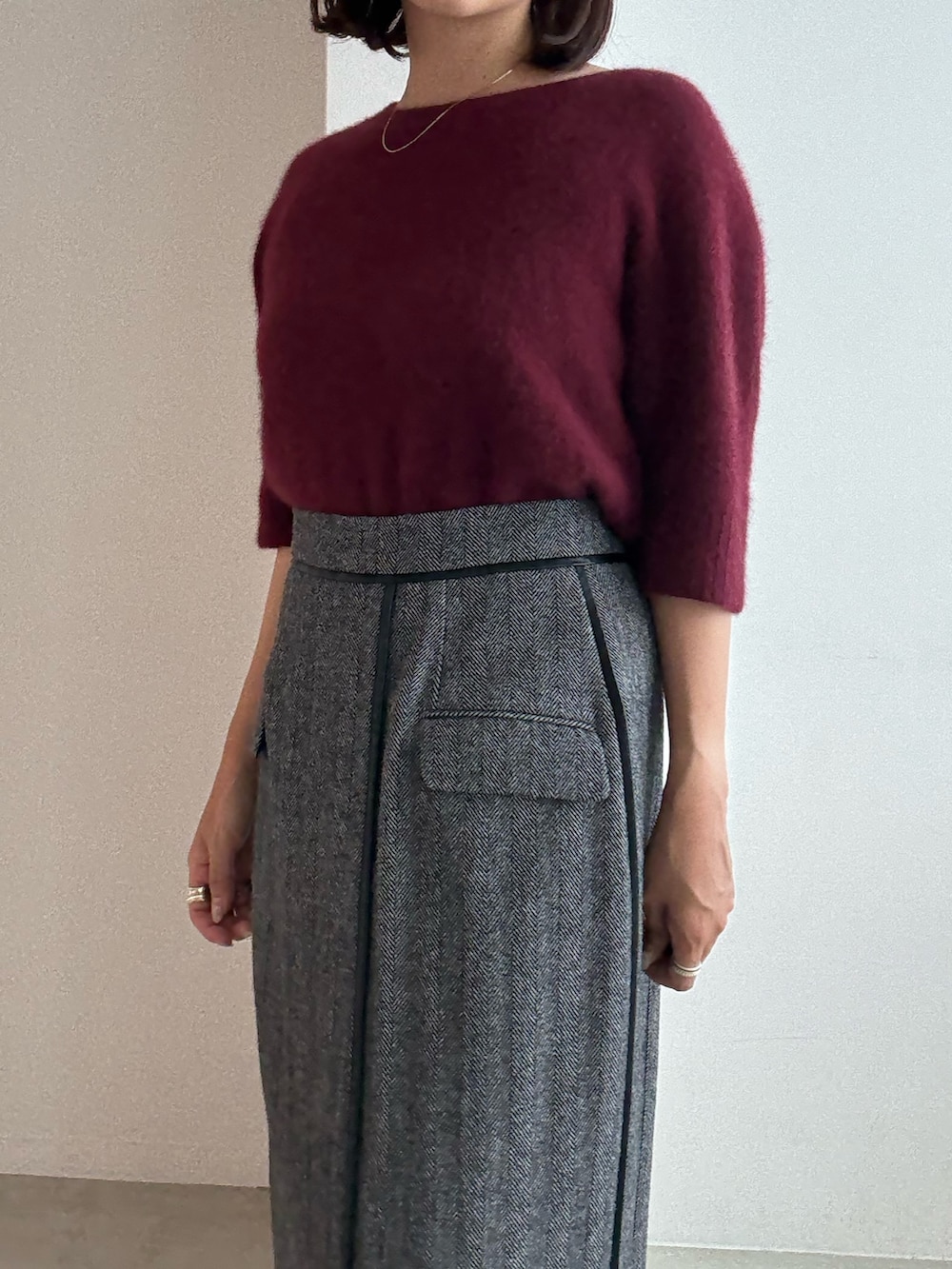 レッド系のニット/セーター、グレー系のスカート、ブラック系のパンプスを着用したレディースの秋コーディネートの5枚目の写真