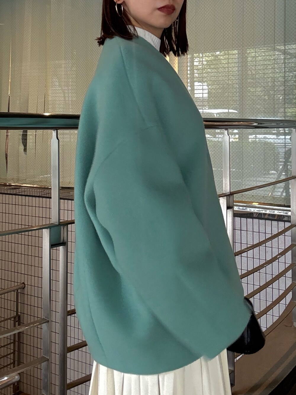 ホワイト系のニット/セーター、ホワイト系のスカート、グリーン系のノーカラージャケットを着用したレディースの秋コーディネートの6枚目の写真