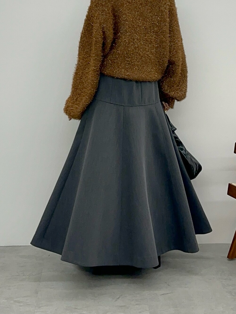 オレンジ系のニット/セーター、グレー系のスカート、ブラック系のブーツを着用したレディースの秋コーディネートの9枚目の写真