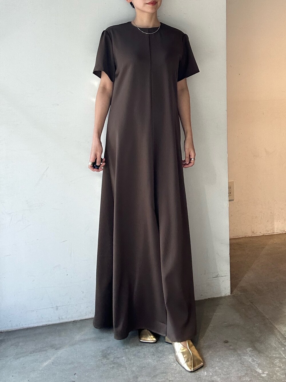 ブラウン系のワンピース、ゴールド系のパンプスを着用したレディースの春コーディネートの2枚目の写真