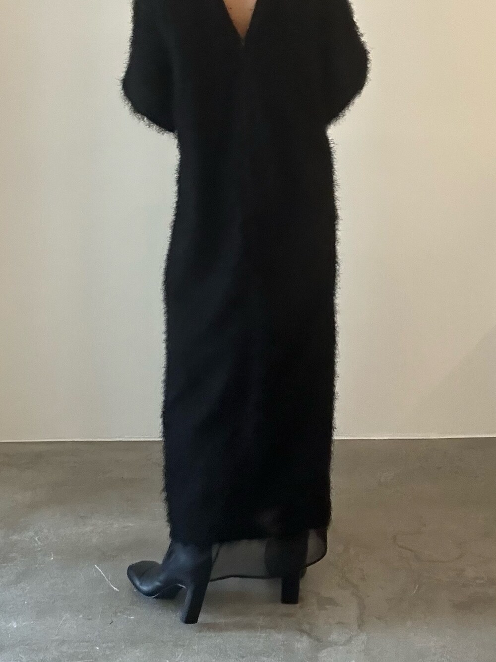 ブラック系のワンピース、シルバー系のハンドバッグ、ブラック系のブーツを着用したレディースの秋コーディネートの7枚目の写真