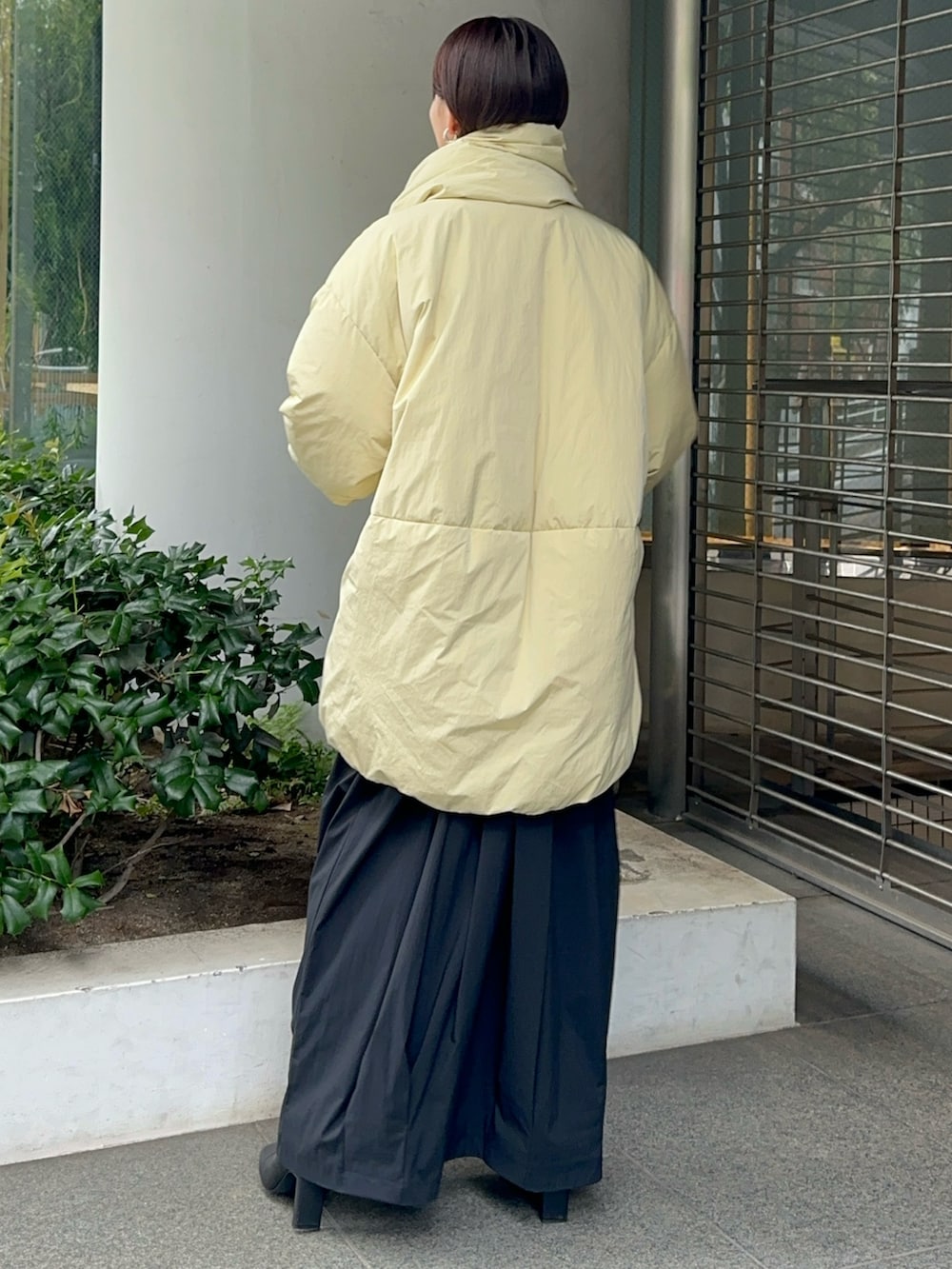 イエロー系のダウンジャケット/コート、グレー系のワンピース、ブラック系のブーツを着用したレディースの夏コーディネートの2枚目の写真