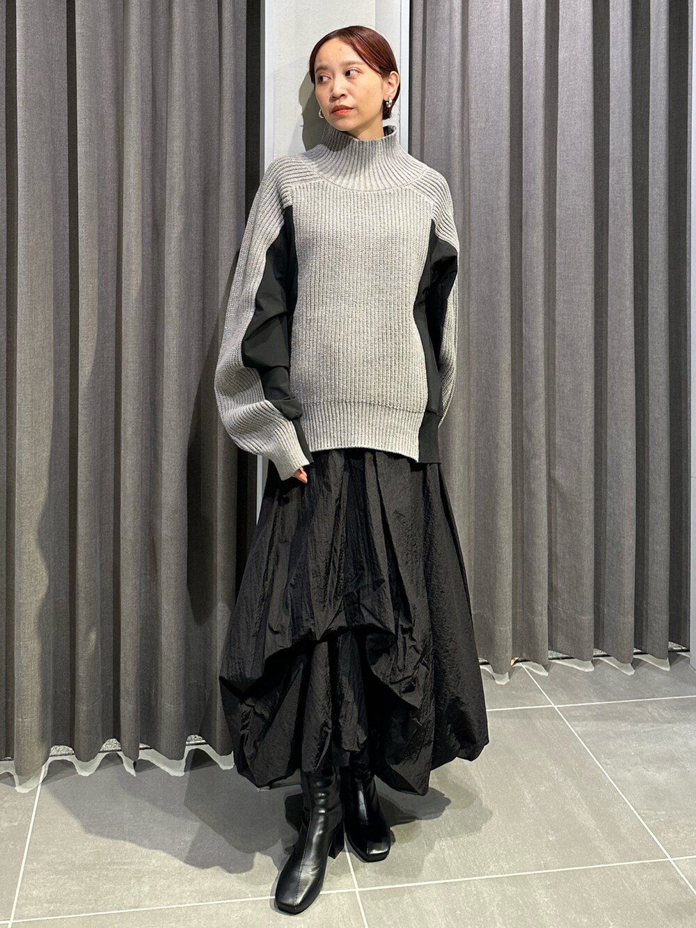 ブラック系のブーツ、ブラック系のスカート、グレー系のニット/セーターを着用したレディースの秋コーディネートの3枚目の写真