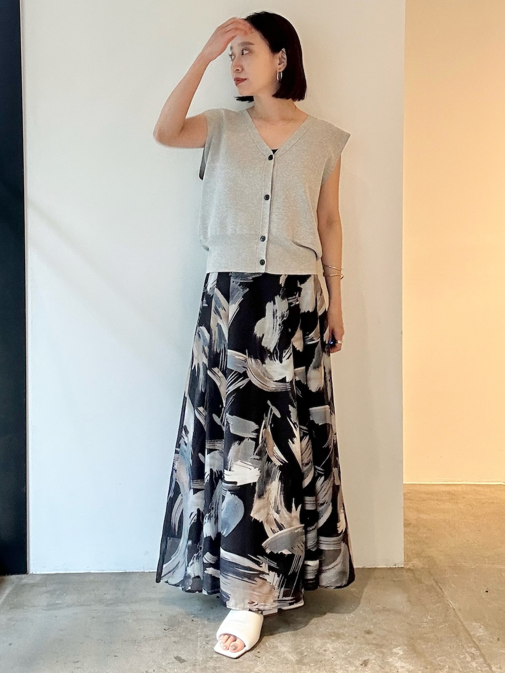 ブラック系のスカート、ホワイト系のサンダル、グレー系のニット/セーターを着用したレディースの春コーディネートの2枚目の写真