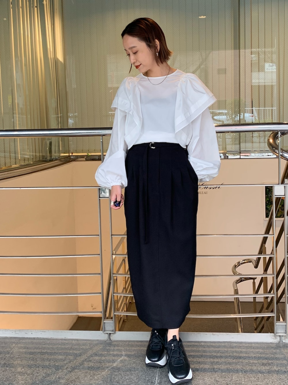 ホワイト系のシャツ/ブラウス、ブラック系のスカート、ブラック系のスニーカーを着用したレディースの春コーディネートの2枚目の写真