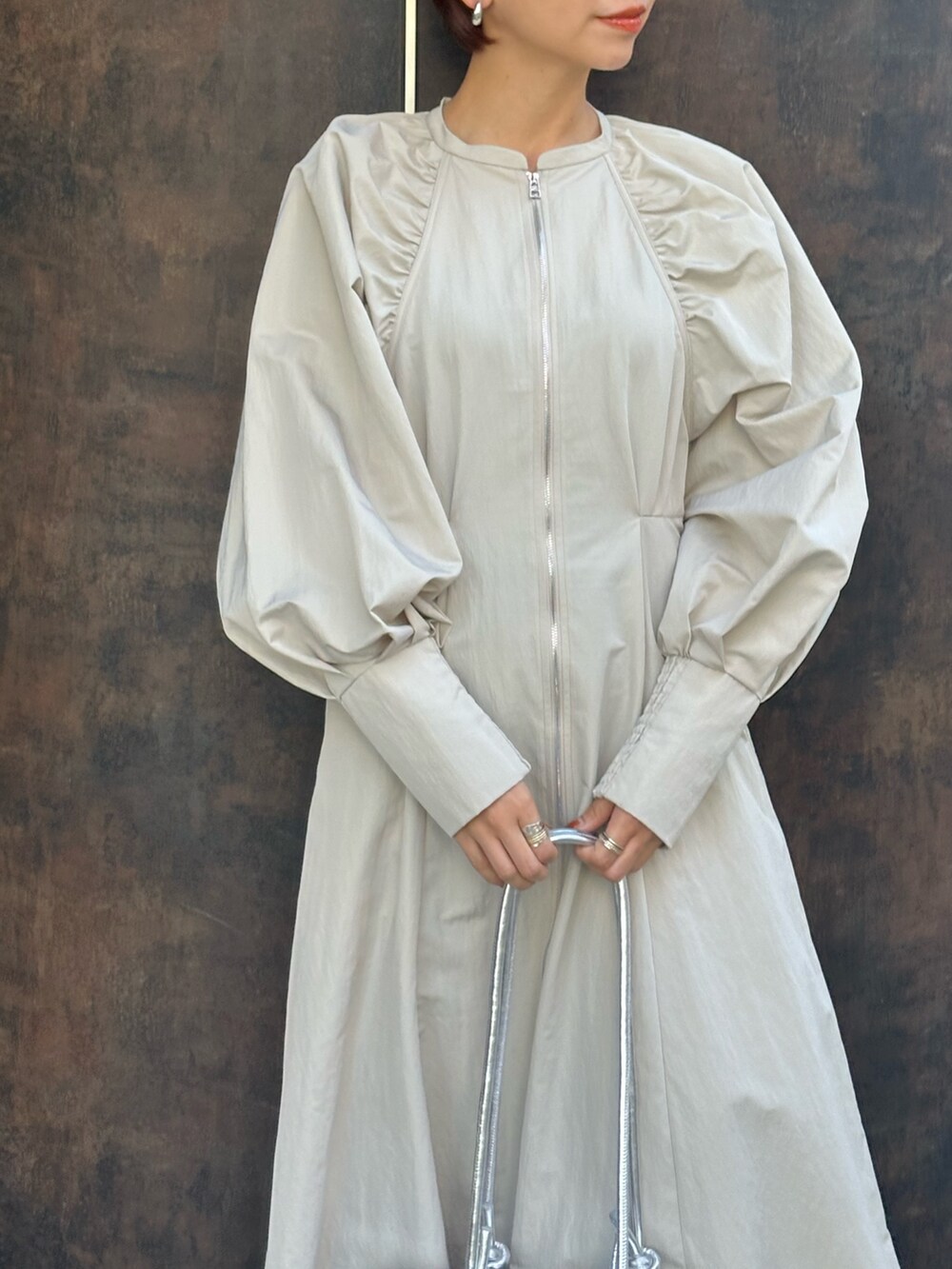 シルバー系のボストンバッグ、ブラック系のブーツ、ベージュ系のワンピースを着用したレディースの冬コーディネートの6枚目の写真