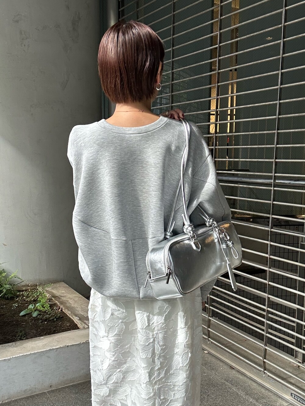 グレー系のスウェット、ホワイト系のスカート、シルバー系のボストンバッグを着用したレディースの冬コーディネートの7枚目の写真