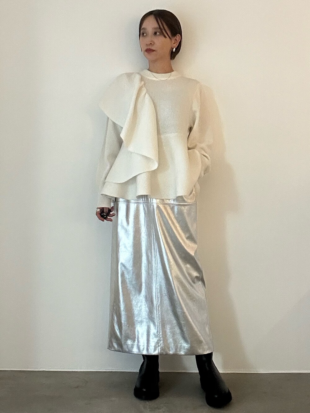 ホワイト系のニット/セーター、ブラック系のブーツ、シルバー系のスカートを着用したレディースの秋コーディネートの2枚目の写真