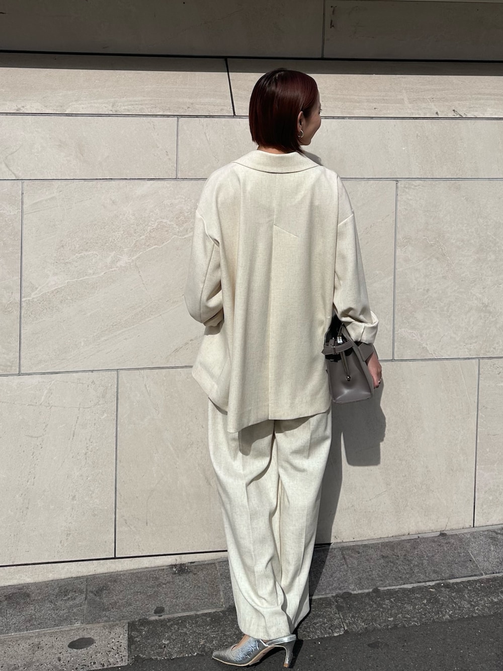 グレー系のハンドバッグ、ベージュ系のその他パンツ、シルバー系のサンダルを着用したレディースの春コーディネートの3枚目の写真