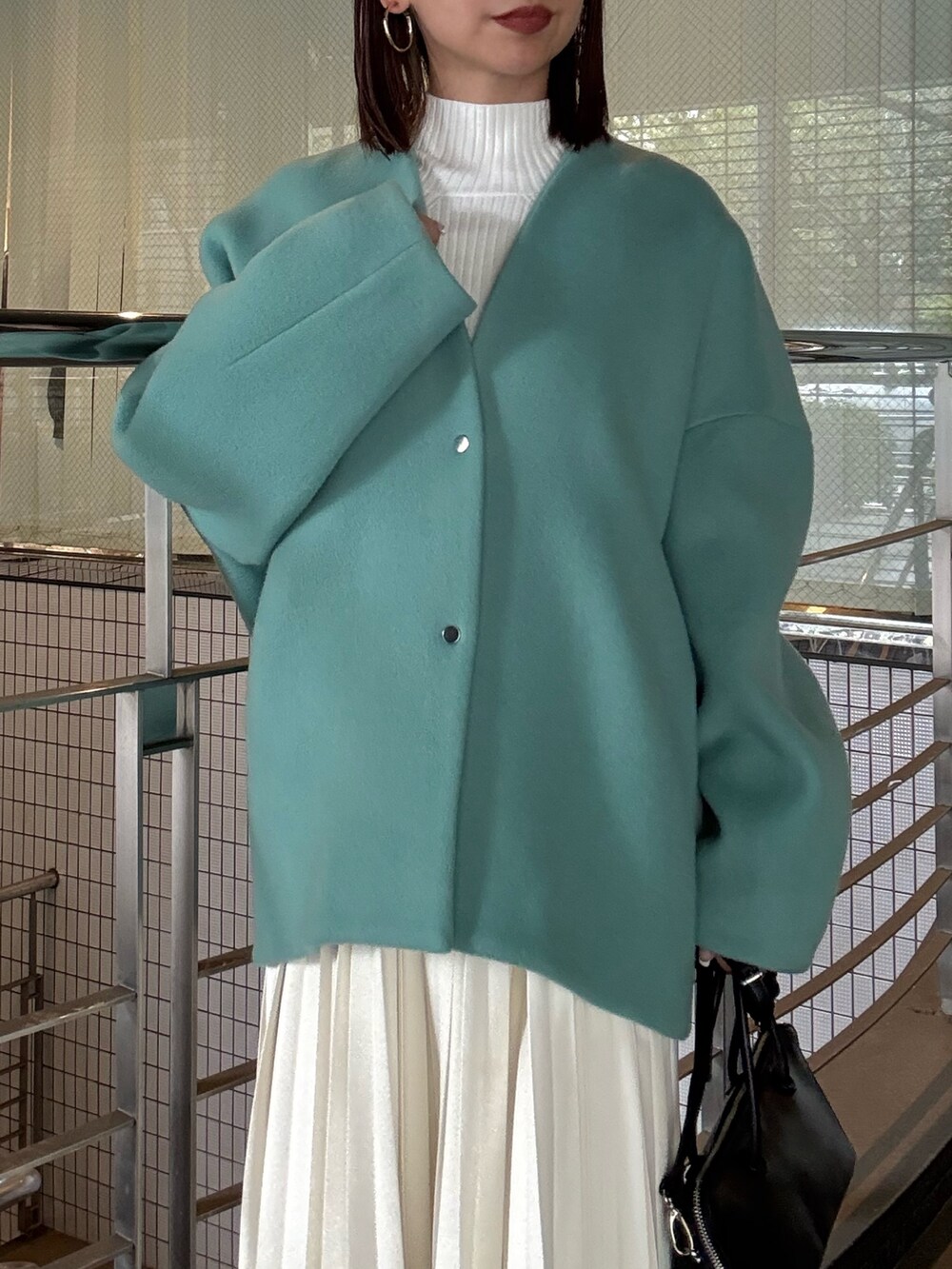 ホワイト系のニット/セーター、ホワイト系のスカート、グリーン系のノーカラージャケットを着用したレディースの秋コーディネートの5枚目の写真